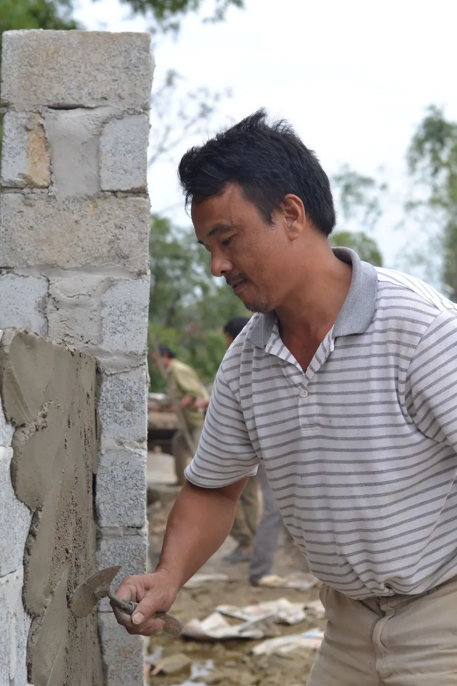 A builder applying cement render to a wall by hand