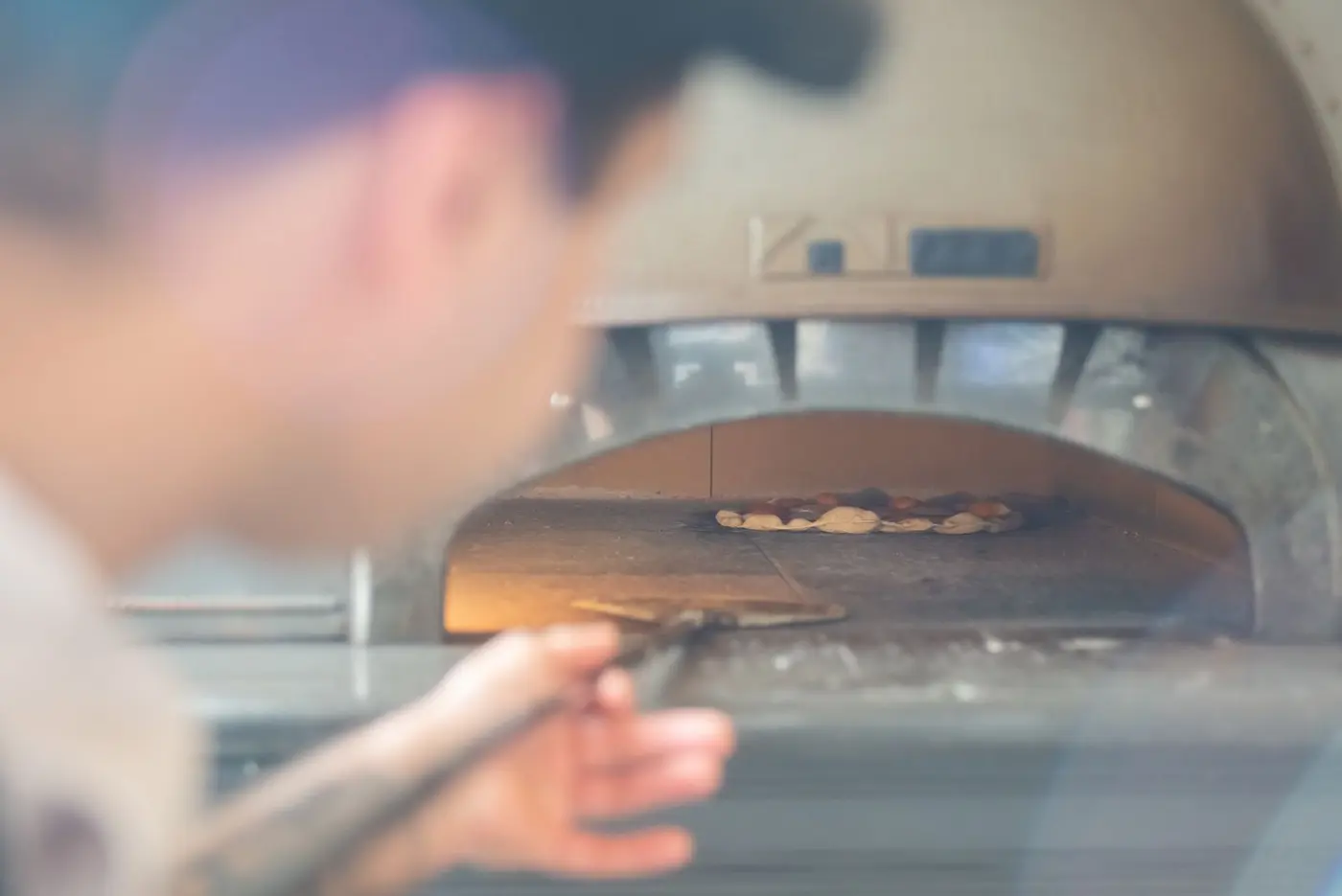 A person inspecting the interior of a brick oven